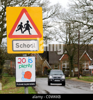 Roadside school sign and 20 mph please slow down signage on an approach road to a country school Hampshire UK Stock Photo