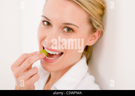 Healthy lifestyle - portrait of woman bite grape on white background Stock Photo