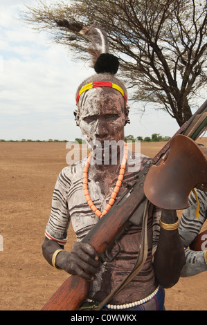 Karo warrior with body and facial paintings holding a rifle, Omo river valley, Southern Ethiopia Stock Photo
