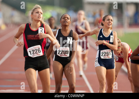 African-American, Anglo girls cross finish line at end of their race at Texas state high school championship meet in Austin Stock Photo