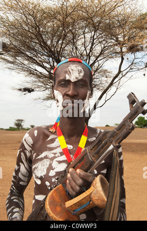 Karo warrior with body and facial paintings holding a rifle, Omo river valley, Southern Ethiopia Stock Photo