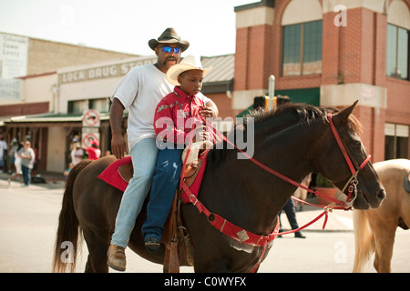 African-American man and boy ride a horse during a parade celebrating Juneteenth in downtown Bastrop, Texas Stock Photo