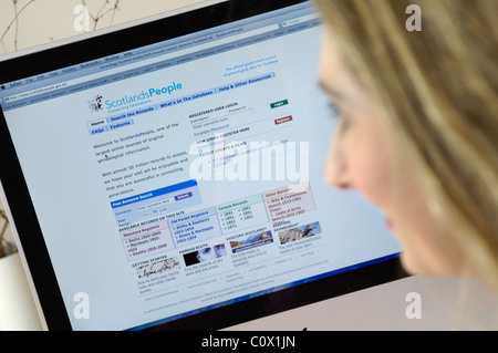 young women researching family history online with books and computer Stock Photo