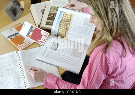 young women researching family history online with books and computer Stock Photo
