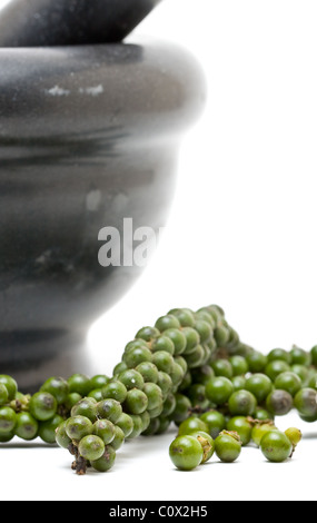 Unprocessed green peppercorns with mortar over white background Stock Photo