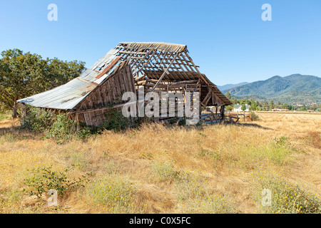 Old dilapidated barn falling apart in field of farm/ranch in Applegate Valley, Oregon. Stock Photo
