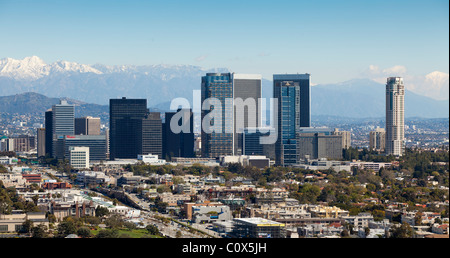 Skyline of Century City area of Los Angeles after a winter storm featuring snow on mountains in background.
