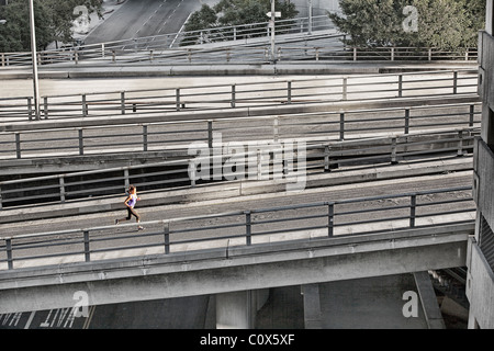 Female runner running on urban city street bridge, overpass in Los Angeles, California