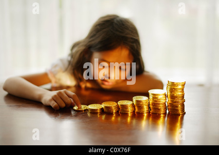 Investing in gold. Girl with stacked chocolate gold coins.