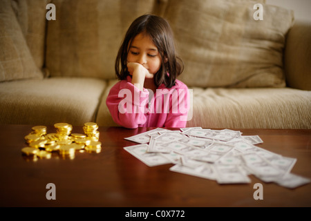 Girl makes investment decision between chocolate gold coins and paper US dollars Stock Photo