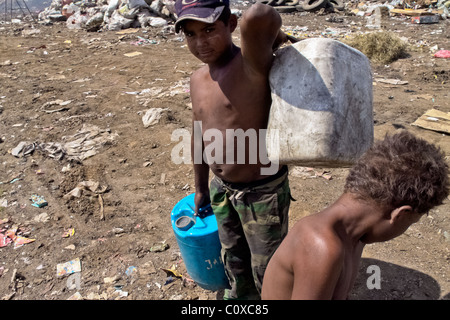 A Nicaraguan boy carries barrels of contaminated water for drinking in the garbage dump La Chureca, Managua, Nicaragua. Stock Photo