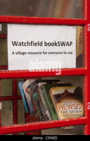 A UK village's redundant BT red telephone box now adopted by the parish council, and converted into a 'Bookswap' mini library. Stock Photo