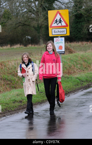 Schoolchildren walking from school along a country lane with no pavement Hampshire England UK Stock Photo