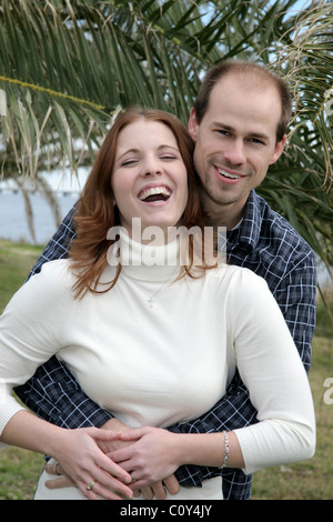A young married couple have fun with posing in a park in front of palm trees. Stock Photo