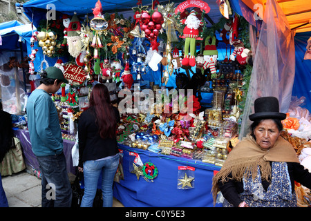 Couple shopping st stall owned by an Aymara lady (front right) in Christmas market , La Paz , Bolivia Stock Photo