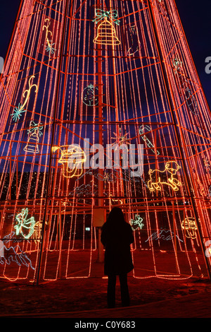 Woman looking at artificial Christmas tree made of red light strips in La Paz, Bolivia Stock Photo