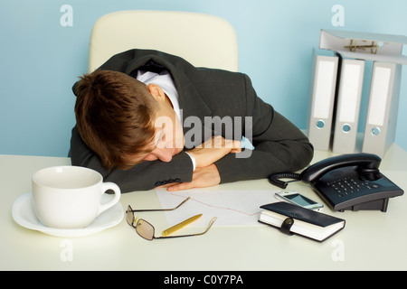 The young man fell asleep on the desktop in the office Stock Photo