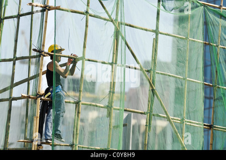 Worker standing in bamboo scaffold on a Hong Kong construction site. Stock Photo