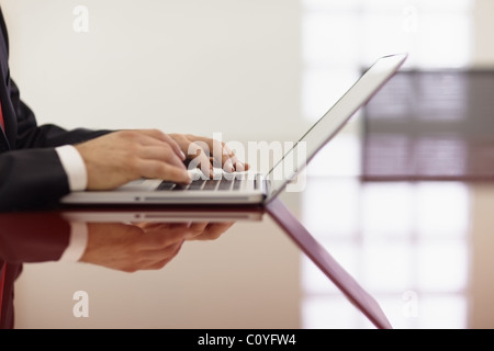 closeup of caucasian mid adult male typing on laptop pc in meeting room. Horizontal shape, side view, copy space