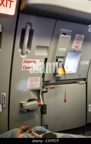 Exit row and emergency exit door, to alight (and emergency escape) from the cabin / fuselage on an Airbus aircraft / airplane / plane / aeroplane. Stock Photo