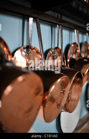 copper cooking utensils hanging on wall Stock Photo