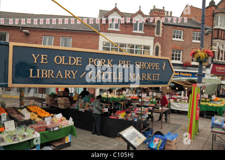 Street sign for the Ye Olde Pork Pie Shoppe with the street market behind, Melton Mowbray, Leicestershire, UK. Stock Photo