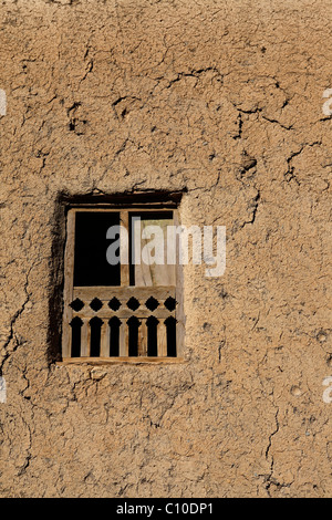 A wooden framed window in one of the red, earth coloured houses of the Omani village of Al Hamra. Stock Photo