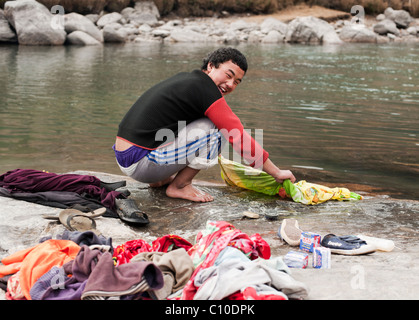 Young Bhutanese boy doing laundry in a river in Bumthang, Bhutan. Stock Photo