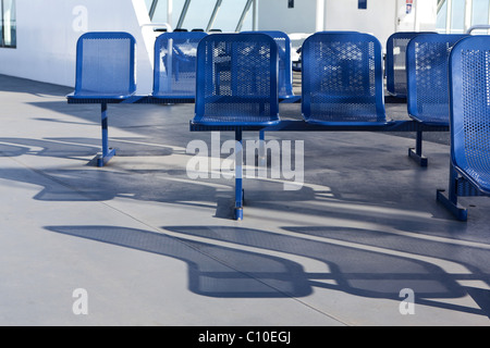 Blue chairs cast shadows on the deck of a BC ferry in Canada. Stock Photo