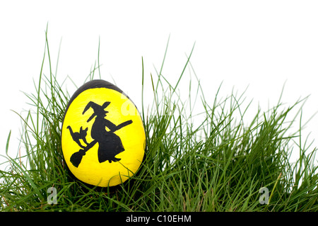 Traditional Scandinavian Easter Witch hand painted on an eggshell, nested in green spring grass Stock Photo