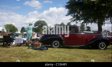 Race goers enjoy  a picnic from the back of their vintage car in a car park at the Royal Ascot race course. Stock Photo