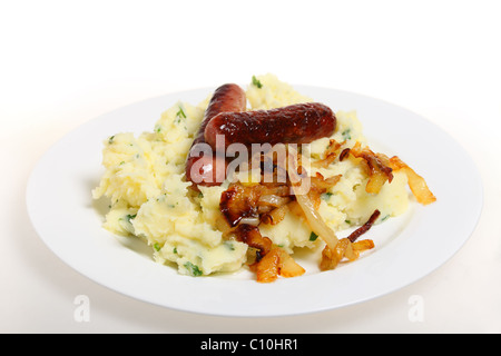 Traditional British 'bangers and mash' meal of sausages with mashed parsley potatoes and caramelised onions on a plate. Stock Photo