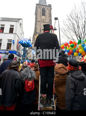 A man up on a ladder to avoid the crowd during the carnival parade in the streets of Cologne (Germany) Stock Photo