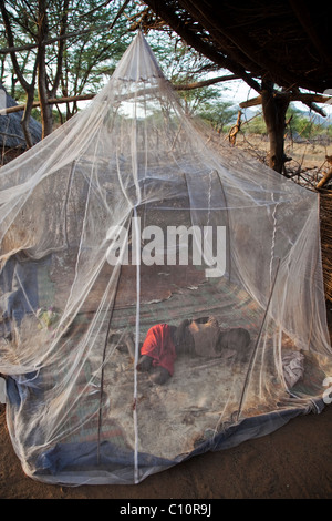 Tsemai girl sleeps under a mosquito net in Ethiopia Stock Photo