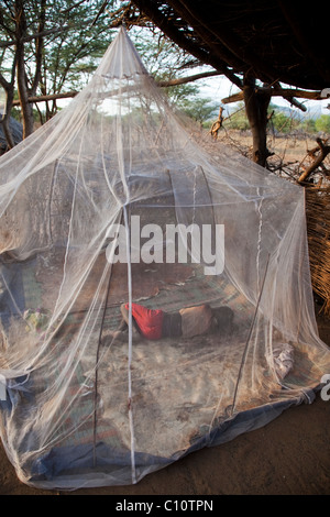 Tsemai girl sleeps under a mosquito net in Ethiopia Stock Photo