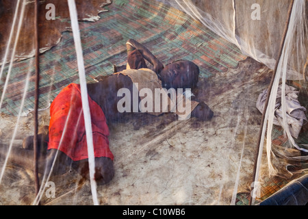 Tsemai girl sleeps under a mosquito net in Ethiopia Stock Photo