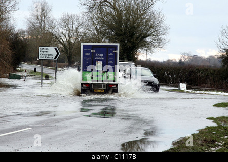 Motorists pass through floods caused by melting snow and ice on the roads in Cricklade near Swindon Wiltshire, England - Stock Photo