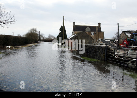 Motorists pass through floods caused by melting snow and ice on the roads in Cricklade near Swindon Wiltshire, England - Stock Photo