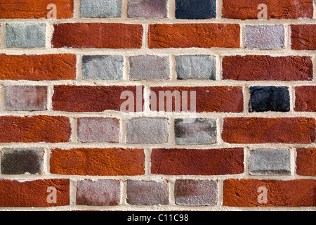 Close-up of a brick wall showing multi-coloured bricks and light mortar. Stock Photo