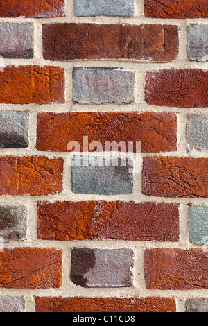Close-up of a brick wall showing multi-coloured bricks and light mortar. Stock Photo
