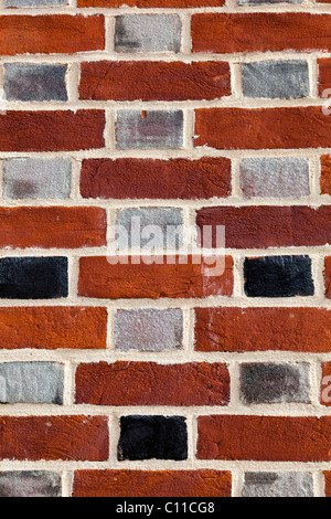 Close-up of a brick wall showing multi-coloured bricks and light mortar. Stock Photo