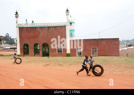 Boys play with old car tyres in front of a  mosque in a small Ugandan town Stock Photo