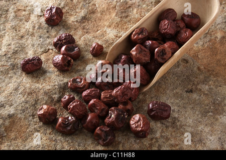 Jujuba berries (Ziziphus jujuba) with a wooden shovel, on stone surface Stock Photo