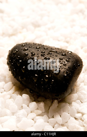 black stone covered with water drops on white pebbles, zen and mindfulness concept Stock Photo