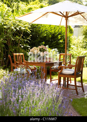 Romantic garden table with lavender bushes in atmospheric sunlight Stock Photo