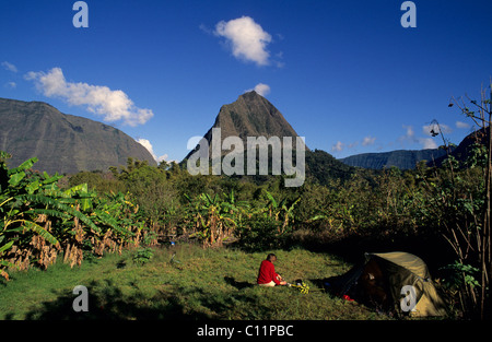 Hiker and tent in a banana plantation in front of Mt. Piton Cabris, 1435m, Cirque de Mafate, Ile de La Reunion, France, Europe Stock Photo