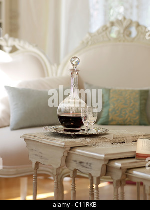 Fine wine carafe with glass on white-painted table, with a stylish sofa Stock Photo