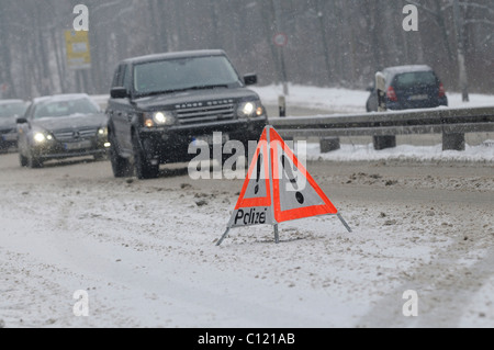 Warning triangle of the police on snow-covered road in front of a traffic jam, Stuttgart, Baden-Wuerttemberg, Germany, Europe Stock Photo