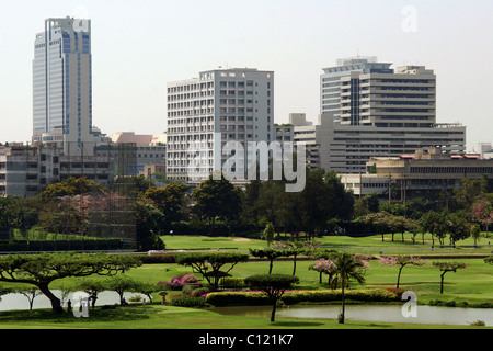 A beautiful green golf course and country club is located near modern buildings in the heart of Bangkok, Thailand. Stock Photo