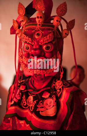 Buddhist monk dressed in ritual dance costume representing a god or demon prepares to dance at a religious festival Stock Photo